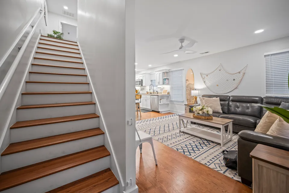 Wooden staircase with white risers and railings leading up from the open-plan living area