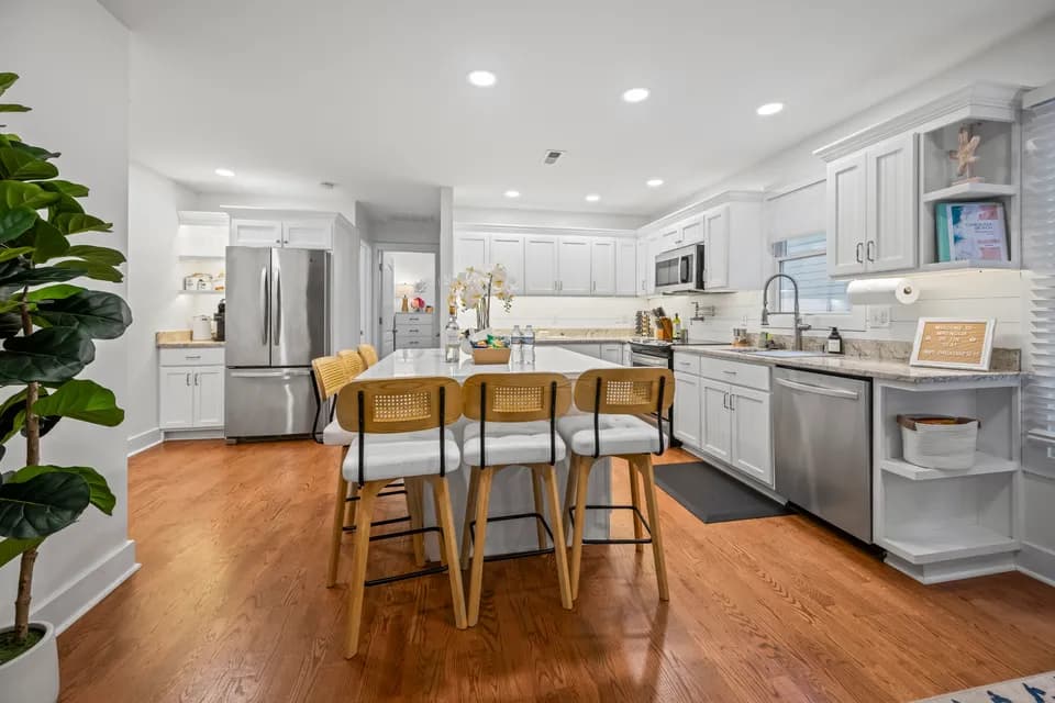 Wood dining table with woven-back chairs seating six, set beside the kitchen island