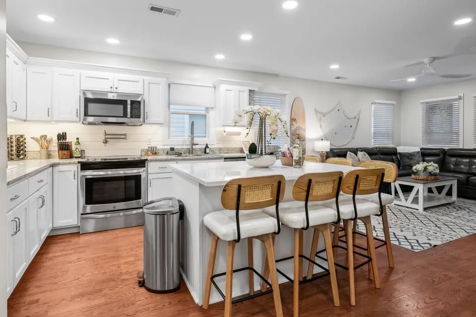 Kitchen with white shaker cabinets, subway tile backsplash, stainless steel appliances, and a large island with counter stools
