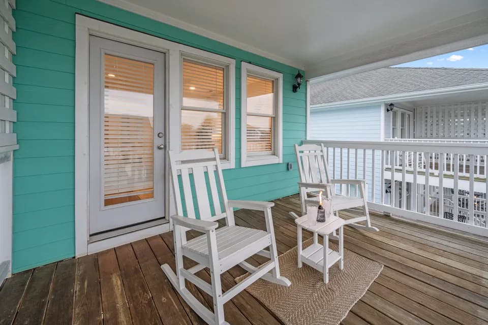 Teal-trimmed covered porch with white rocking chairs and French doors opening to the living room