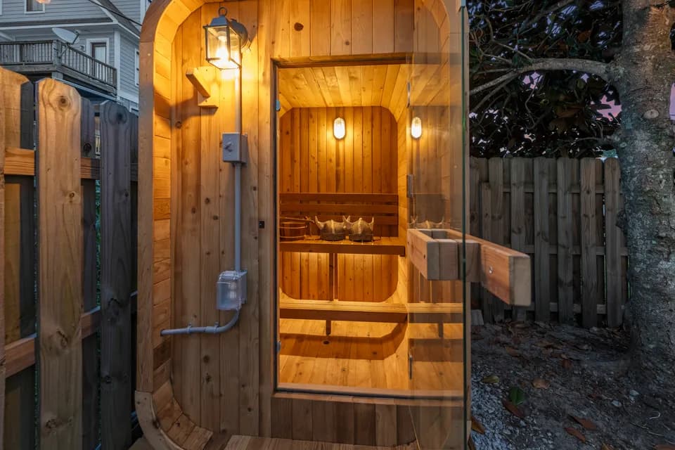 Cedarwood sauna's glowing wood door and exterior lighting at dusk